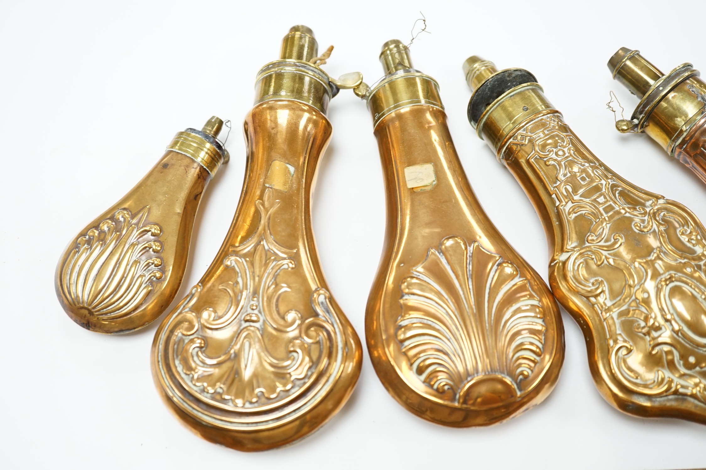 Five 19th century copper and brass powder flasks, all with embossed decoration to the bodies. Condition - fair